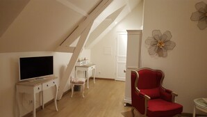 Una habitación con una televisión, una silla roja y un armario blanco.