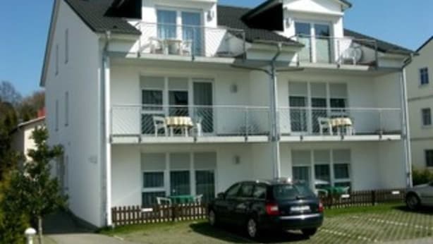 A multi-story residential building with balconies, a car parked in front, and a clear sky. - App. 25 - Apartment house Anne (Binz)