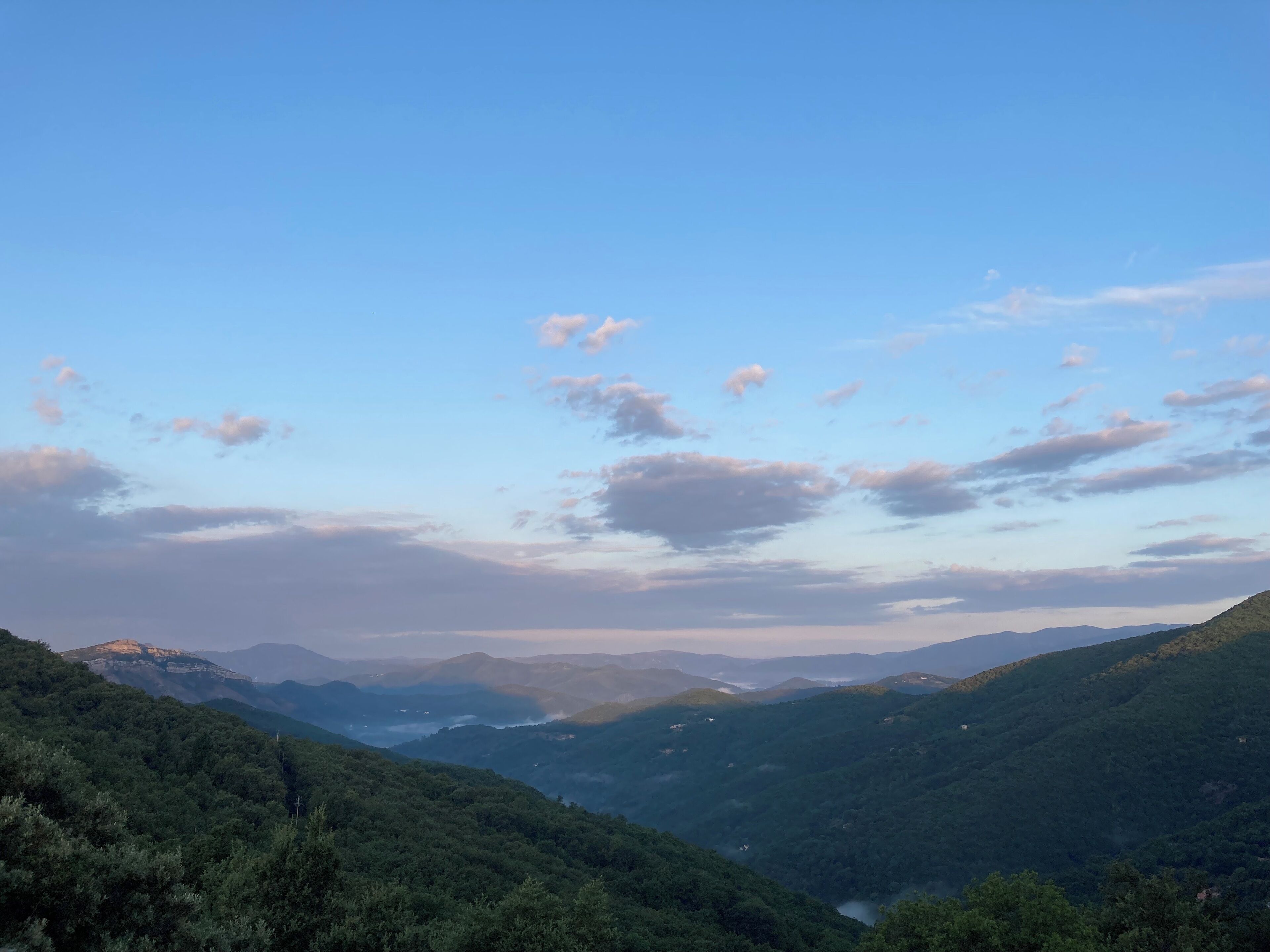 A mountainous landscape with a valley and distant mountains.
