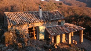 A rustic stone house with a tiled roof, a chimney, and a small porch. - small, cozy eco-house for environmentally conscious nature-lover (Saint-Roman-De-Codières)