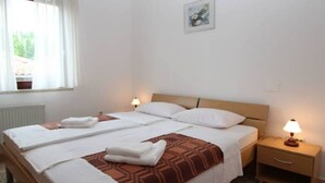 Habitación de hotel con dos camas, una mesita de noche con lámpara y una ventana con cortinas.