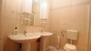 Un baño con dos lavamanos, un inodoro y un espejo.