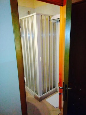 Un baño con cabina de ducha, inodoro y lavamanos.