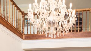 A spacious foyer with a grand chandelier, wooden staircase, and two upholstered chairs. - Moncrieff Manor (Knysna)