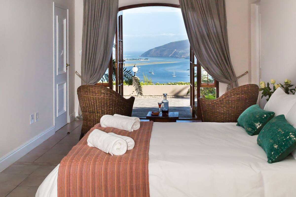 A bedroom with a bed, a view of the sea, and a balcony.