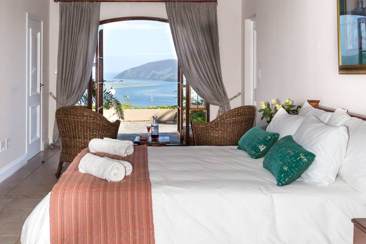 A bedroom with a large bed, a view of the sea, and a balcony.