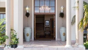 A building entrance with a large arched doorway, flanked by tall columns, and two large planters with potted plants. - Moncrieff Manor (Knysna)