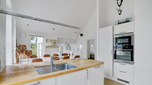 Una cocina moderna con armarios blancos, encimera de madera y horno empotrado.