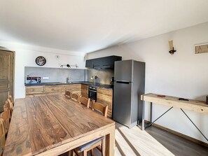 A modern kitchen with a wooden dining table, built-in appliances, and a minimalist design.