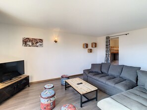 A modern living room with a sofa, a coffee table, a TV, and decorative items.