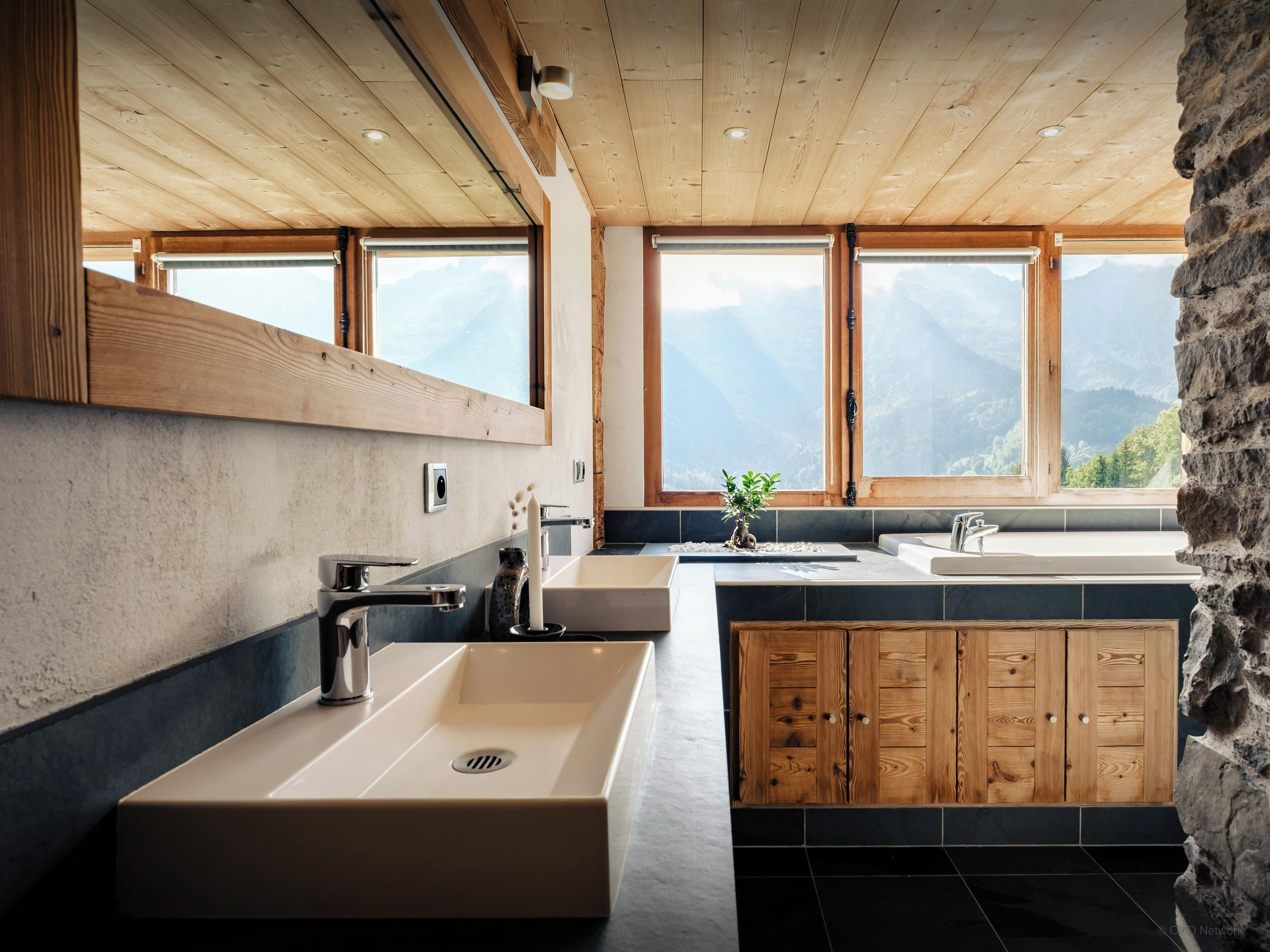 Une cuisine moderne avec des meubles en bois, un grand évier et une vue sur les montagnes grâce à de grandes fenêtres.