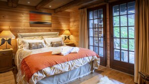 Ein gemütliches Schlafzimmer mit einem großen Bett, zwei Nachttischlampen, einem flauschigen Teppich und einem Fenster mit Vorhängen.