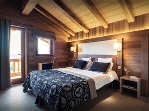 Un dormitorio de cabaña de madera con una cama, lámparas de noche y vistas por una ventana.