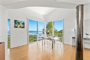 A modern dining area with a glass table, clear chairs, and a view of the ocean. - "Calypso House - HYERES (HYERES)