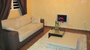 A living room with a beige sofa, a small coffee table with a plant, and a white rug.