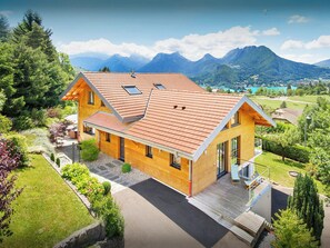 Ein zweistöckiges Haus mit geneigtem Dach, einem Balkon und Blick auf Berge.