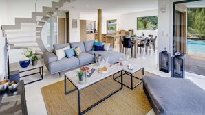 Ein modernes Wohnzimmer mit grauem Sofa, einem Couchtisch und einer Treppe, die zu einer anderen Ebene führt.