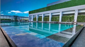 A modern pool area with clear water, a green wall, and a row of columns. - Amazing apartment Miami Brickell with spectacular views  (Miami)