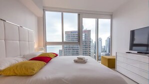 A modern hotel room with a large bed, a television, and a city view. - Amazing apartment Miami Brickell with spectacular views  (Miami)