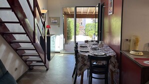 Un comedor con una mesa dispuesta para dos, una escalera y vistas al exterior.