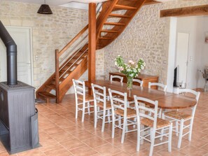A dining area with a wooden table and chairs, a stone wall, and a staircase. - Charming getaway in Touraine, near castles and nature (Sennevières)