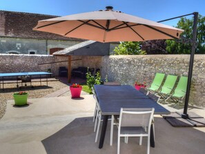 An outdoor patio with a table and chairs, a large umbrella, and potted plants.