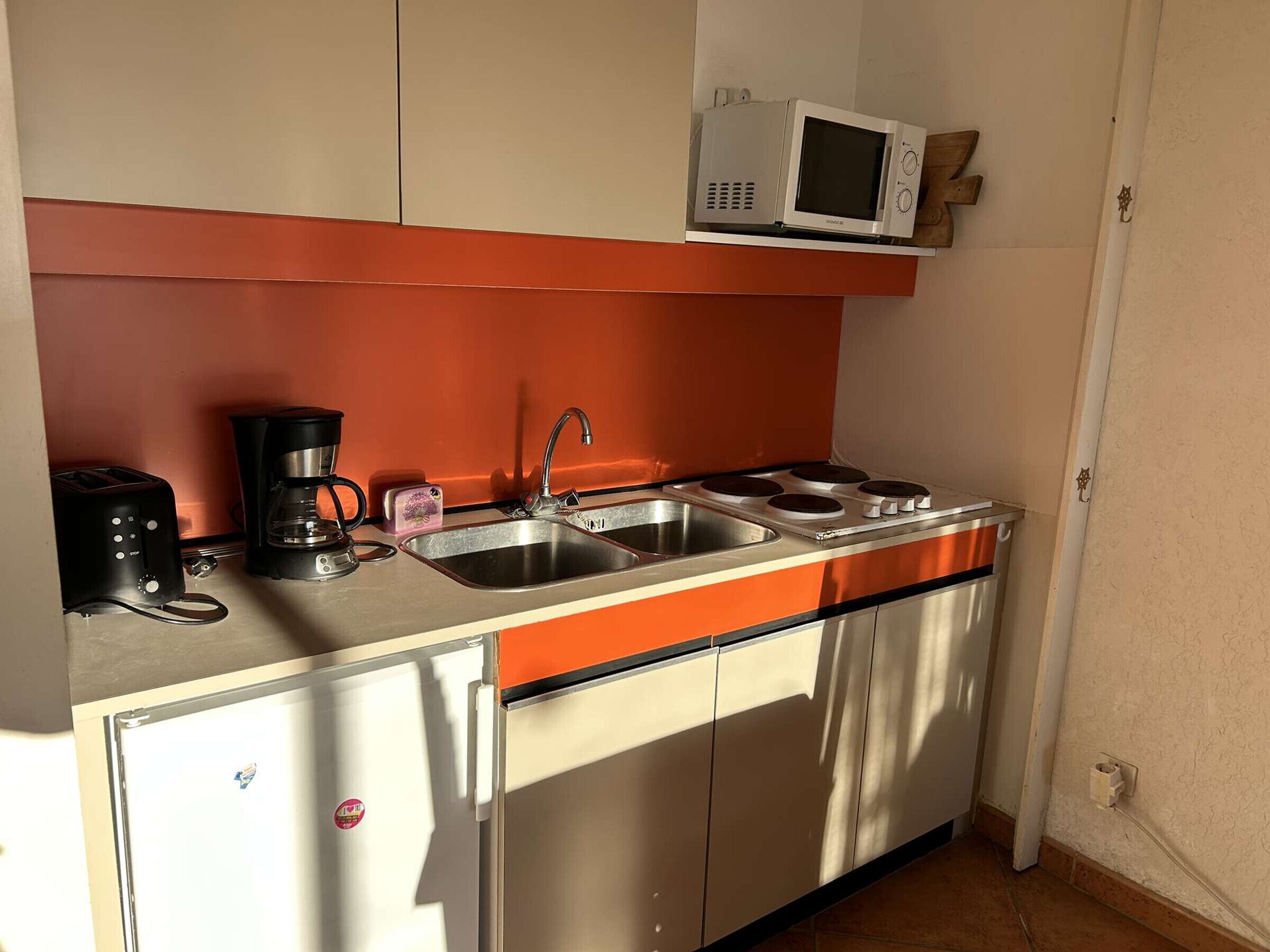 A compact kitchen with a sink, stove, and microwave.