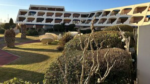 Un bâtiment moderne doté de nombreux balcons et d’une cour intérieure agrémentée de palmiers et d’arbustes.