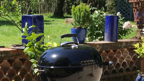 Ein tragbarer Grill auf Rädern, aufgeschichtet auf einem Kiesgrundstück.