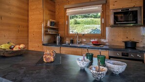 A modern kitchen with wooden walls, a large window, and a built-in oven.