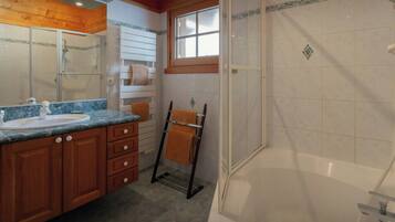 Un baño con ducha, lavamanos y tocador con cajones.