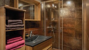 Ein modernes Badezimmer mit einer Duschkabine aus Glas, Holzschränken und einem Waschbecken mit schwarzer Arbeitsplatte.