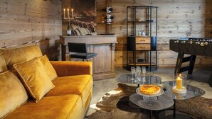 Ein gemütliches Zimmer mit Holzwand, einer Couch, einem Esstisch mit Kuchen und einer Bar.