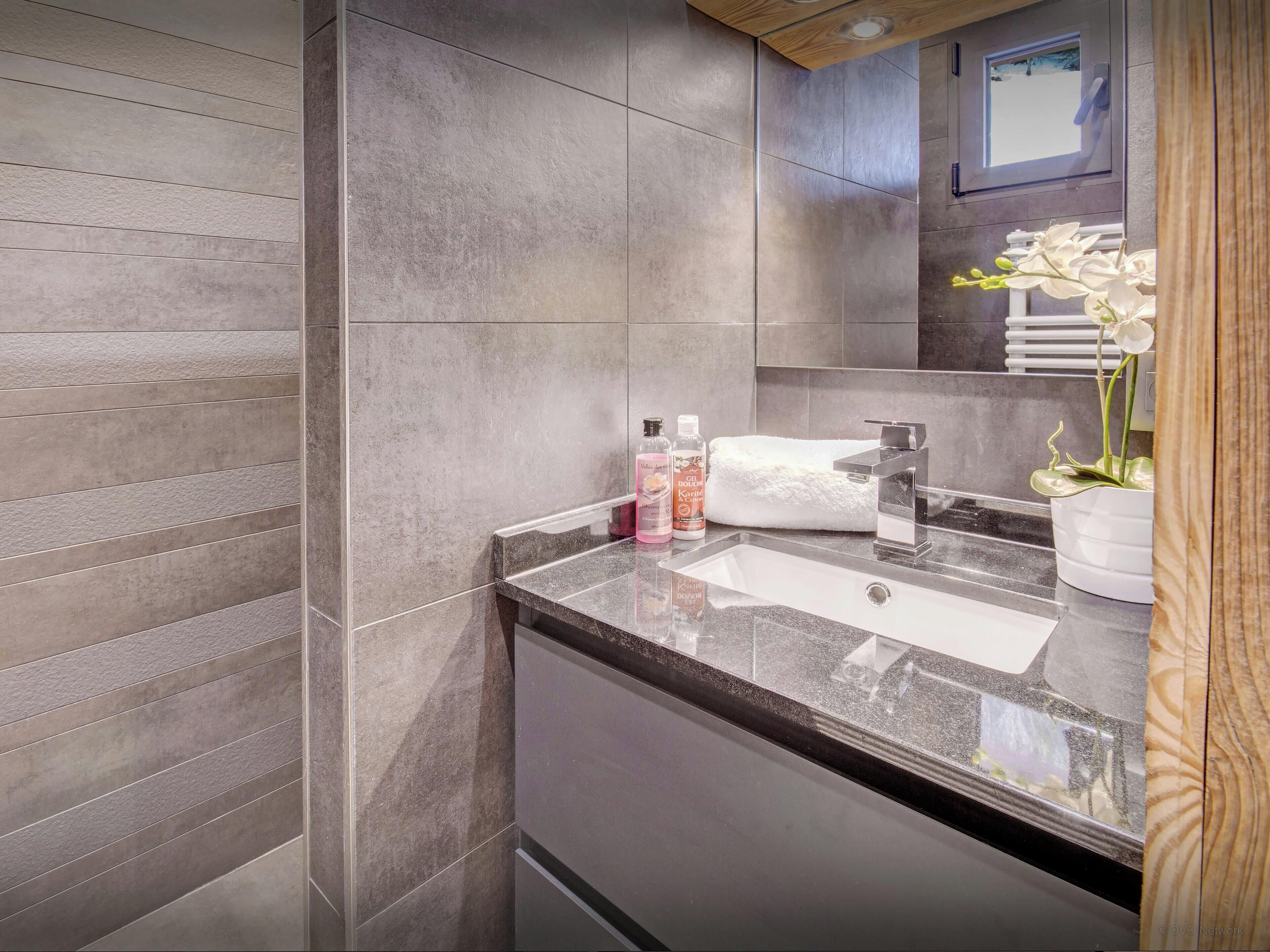 A modern bathroom with a large mirror, a sink, and a towel rack.