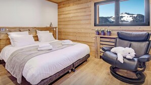 A wooden cabin room with a bed, a massage chair, and a window with a snowy landscape view. - Chalet Charmar - secluded ski-in ski-out chalet for 12 - OVO Network (La Clusaz)