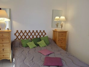 Um quarto com uma cama, duas mesas de cabeceira, um painel de cama de madeira e um espelho na parede.