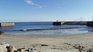 Una playa con un muelle de hormigón y un cartel.