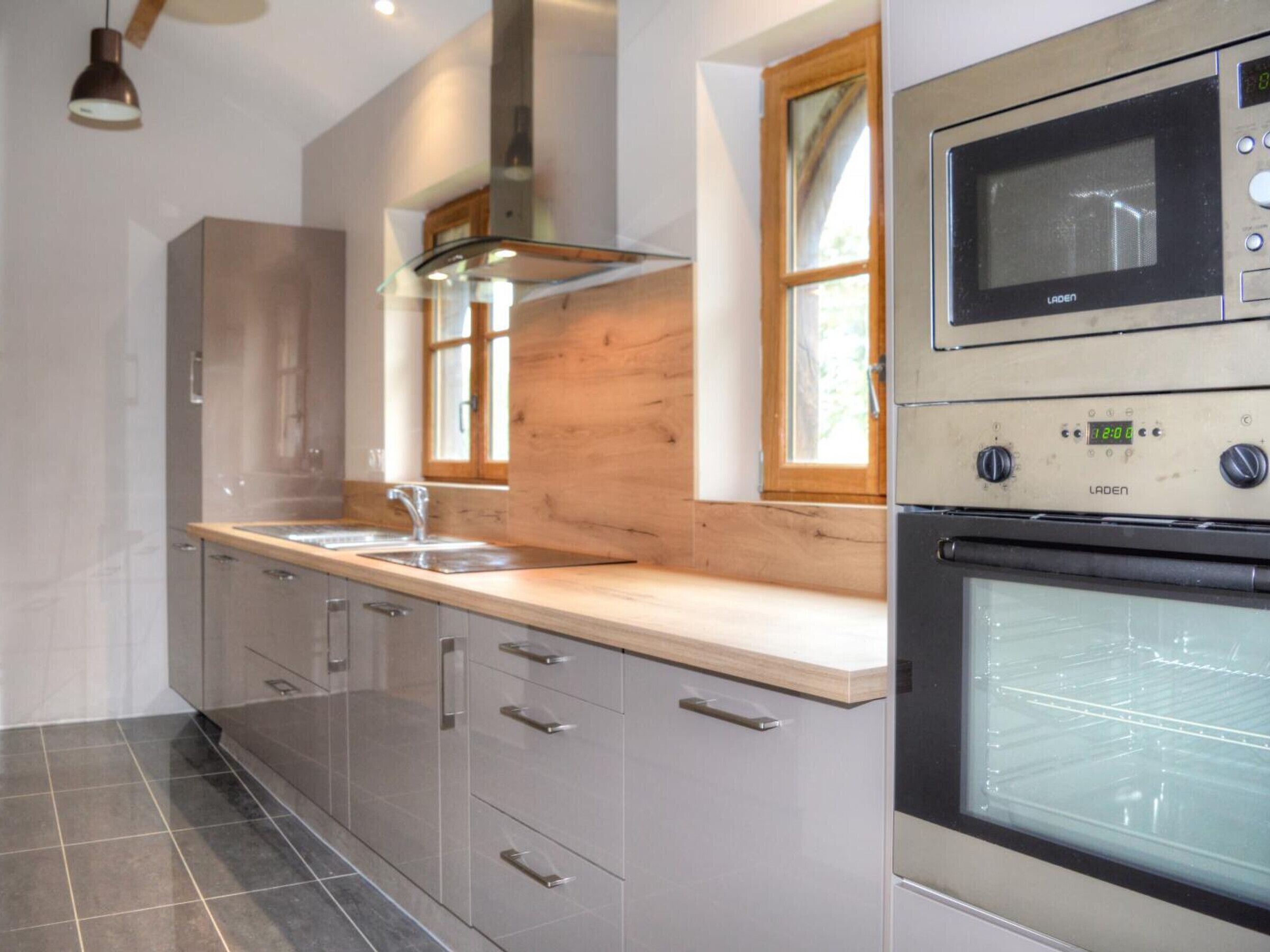 A modern kitchen with stainless steel appliances, a wooden countertop, and a window providing natural light.