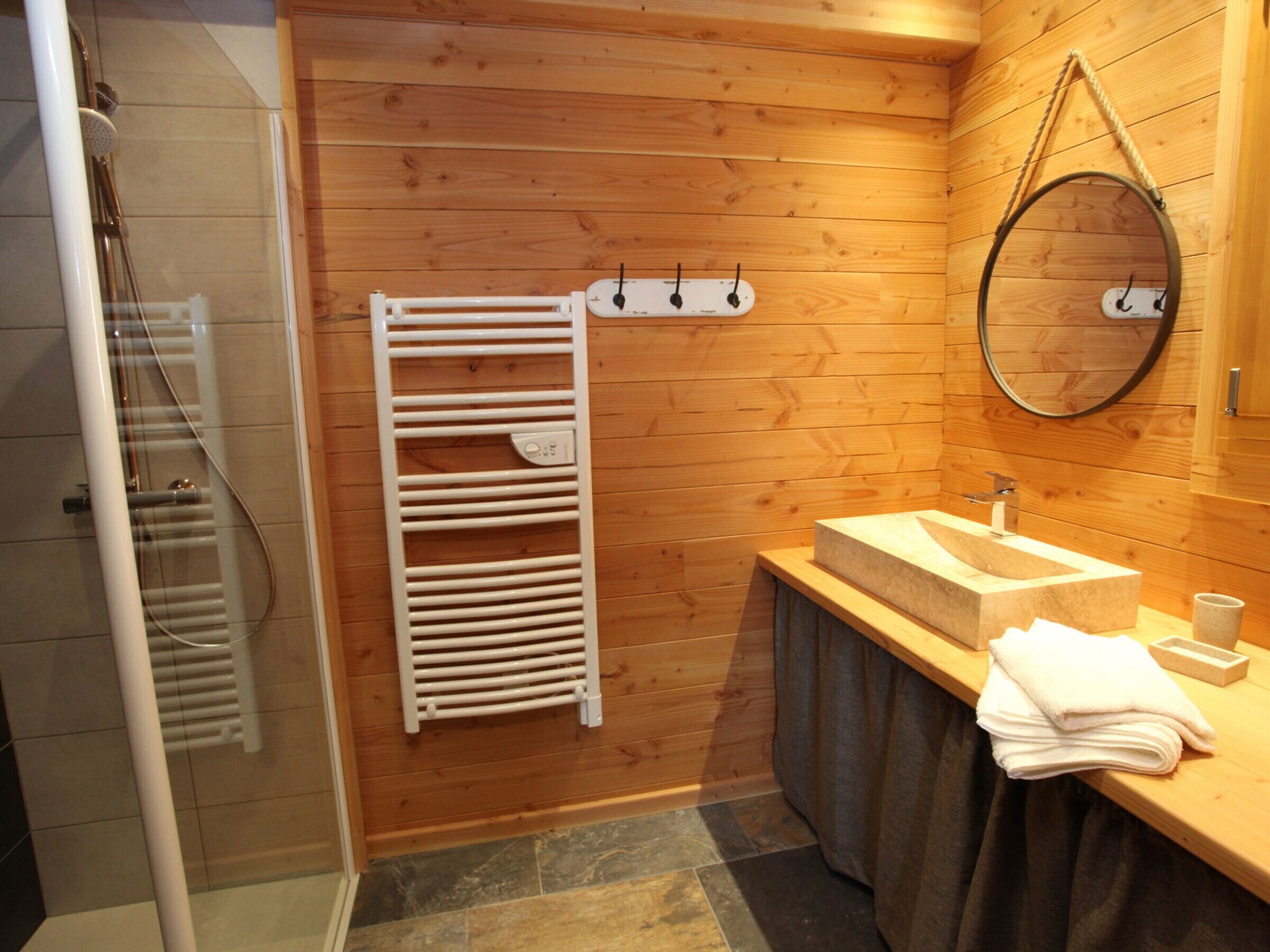 Une salle de bain avec des murs en bois, un porte-serviettes blanc, un lavabo et un miroir.