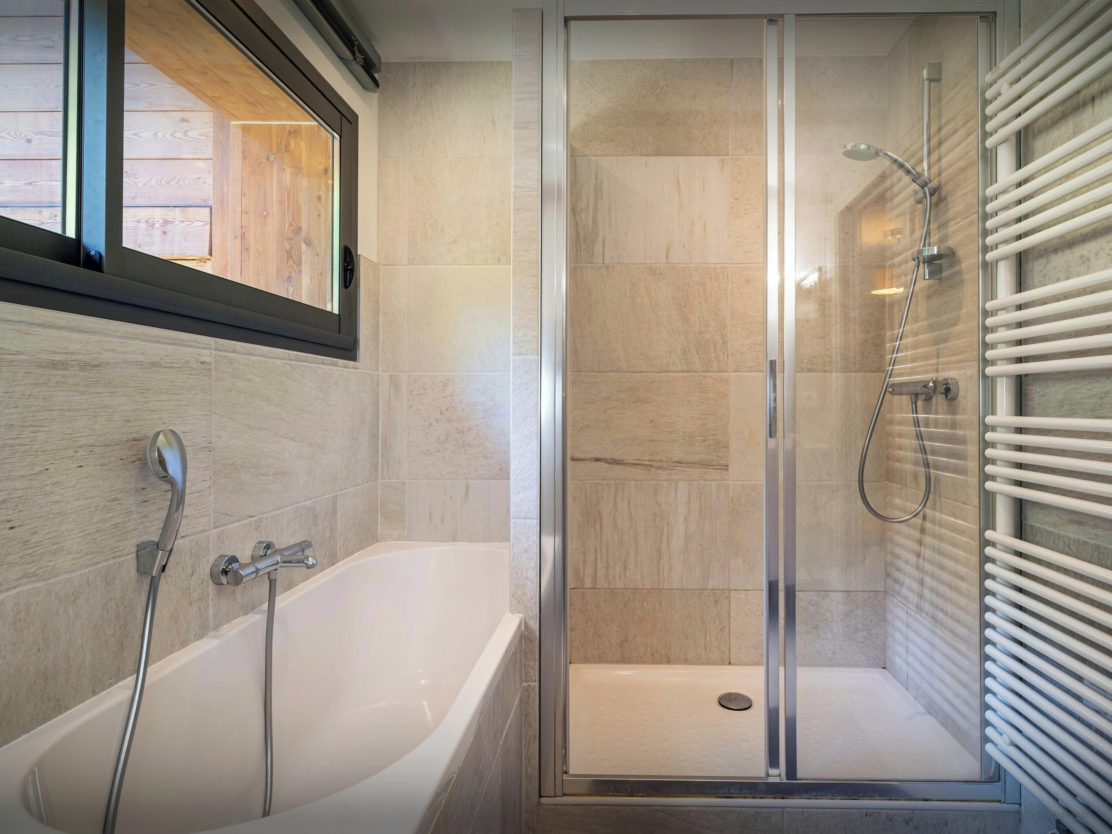 Une salle de bain moderne équipée d’une baignoire, d’une douche et d’un espace de douche séparé par des parois en verre.