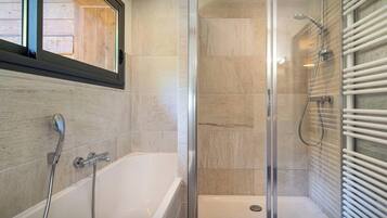 Une salle de bain moderne équipée d’une baignoire, d’une douche et d’un espace de douche séparé par des parois en verre.
