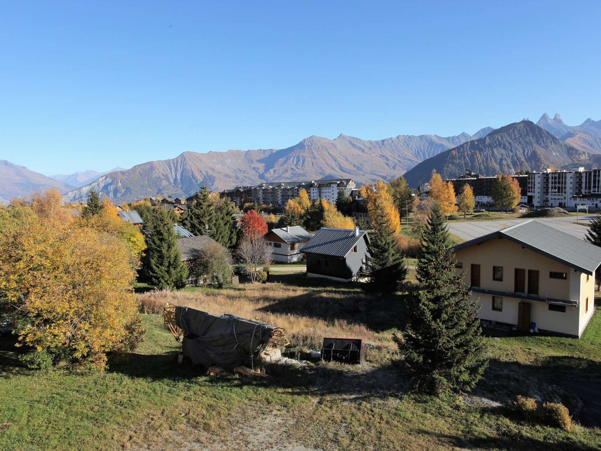 A mountainous landscape with residential buildings, including a large hotel with multiple floors and a flat roof.