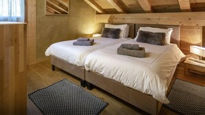 A wooden cabin-style bedroom with a large bed, two bedside tables, and a mirror on the wall. - Chalet Chocolat - Manigod ski base for 8, log fire nights - OVO Network (Manigod)