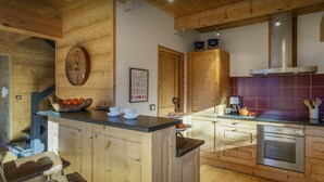 A wooden kitchen with a wooden island, a clock, and a map on the wall. - Chalet Chocolat - Manigod ski base for 8, log fire nights - OVO Network (Manigod)