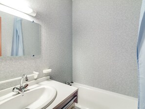 Un baño con lavamanos blanco, un espejo y una bañera.