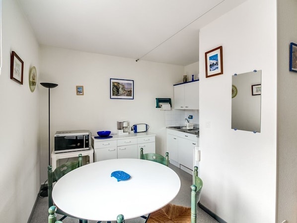 A compact kitchen with white cabinets, a round table, and a blue bowl.