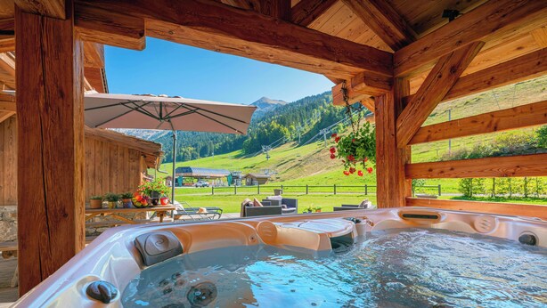 Jacuzzi con techo de madera y vista a un paisaje montañoso.