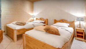 Una habitación con dos camas de madera, cada una con una almohada y una mesita de noche con una lámpara.