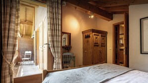 A bedroom with a bed, wooden wardrobe, and a chair.