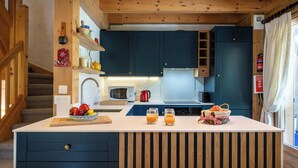 A modern kitchen with wooden beams, a central island, and a built-in microwave.
